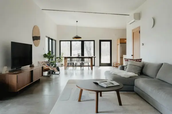 Salón moderno con sofá gris, mesa de centro y comedor. El color gris se combina con tonos madera y blanco, creando un ambiente sereno.