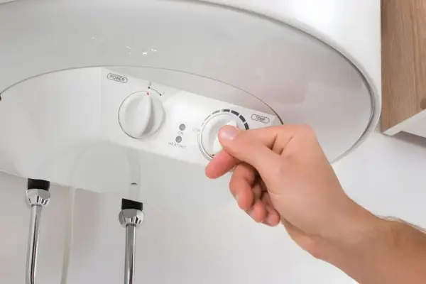 Mano ajustando el termostato de un termo eléctrico. Averigua cuanto dura un termo eléctrico y optimiza su uso.