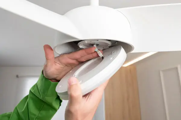 Manos conectando cables para como instalar un ventilador de techo con luz.