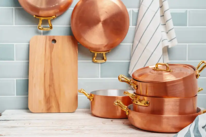 Utensilios de cobre apilados y colgados, listos para aprender como limpiar el cobre y mantenerlos brillantes.